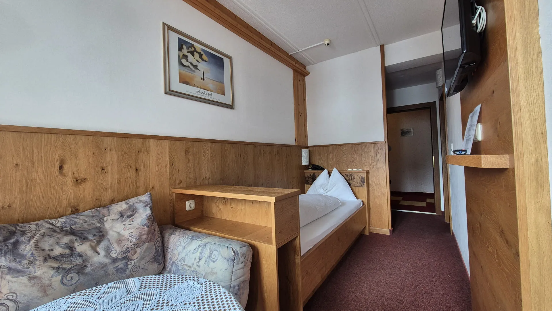 Helle Hotelzimmer mit Holzdetails und Einzelbett