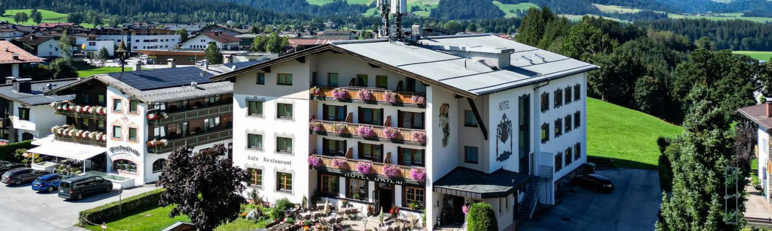 Alpenhotel mit Balkonen und Blumen, umgeben von grünen Wiesen