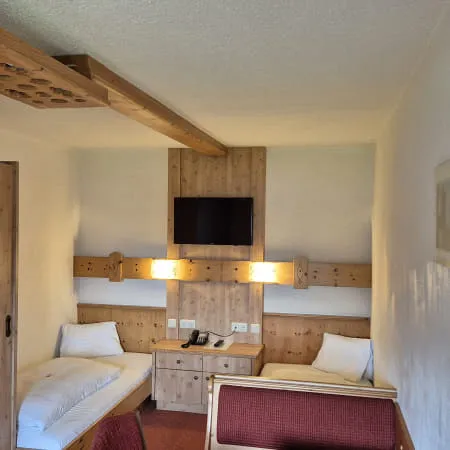 Helles 4-Bettzimmer mit zwei Betten, TV und Holzmobiliar