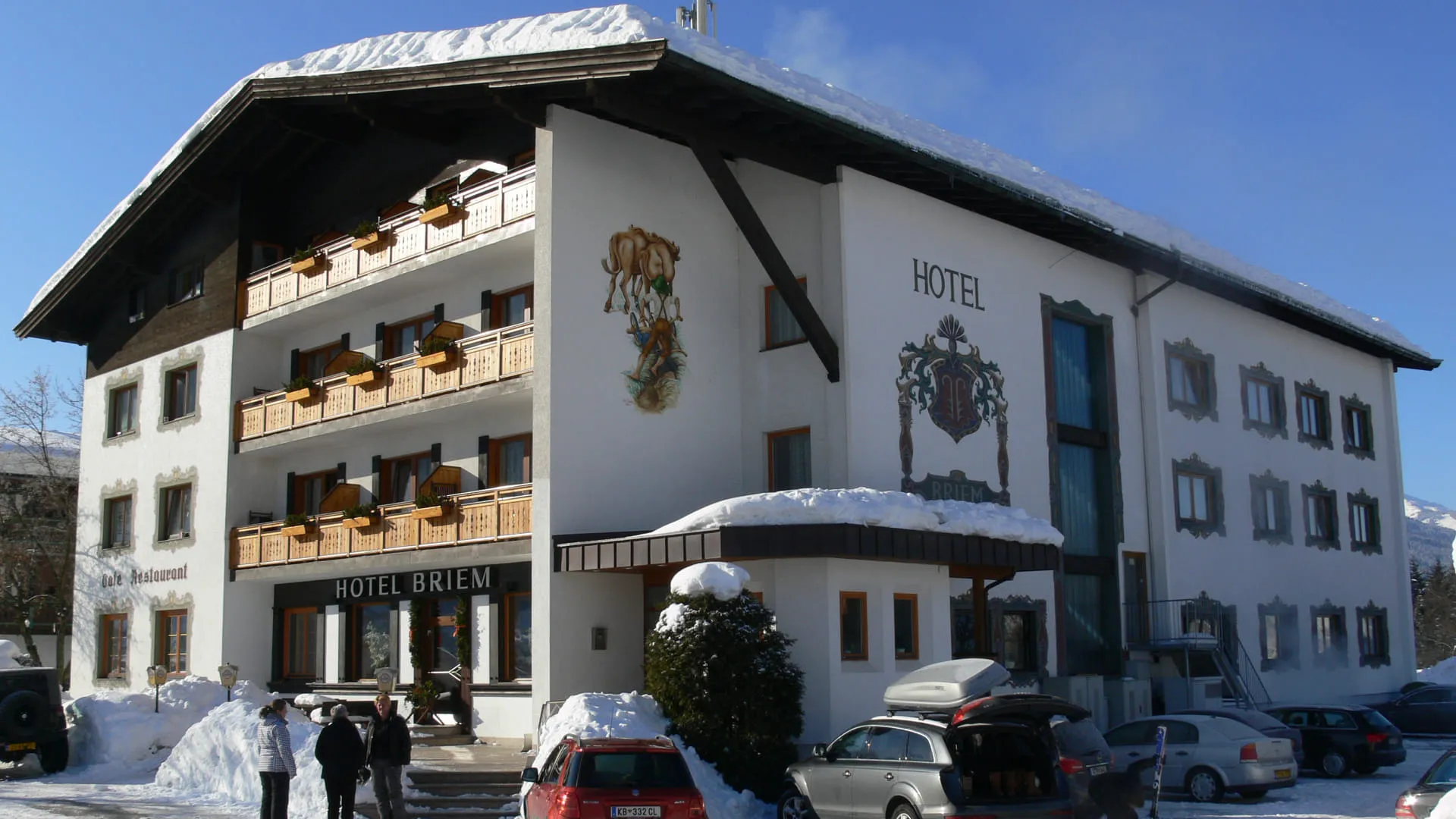 Hotel Briem im Schnee mit Gästen und Autos
