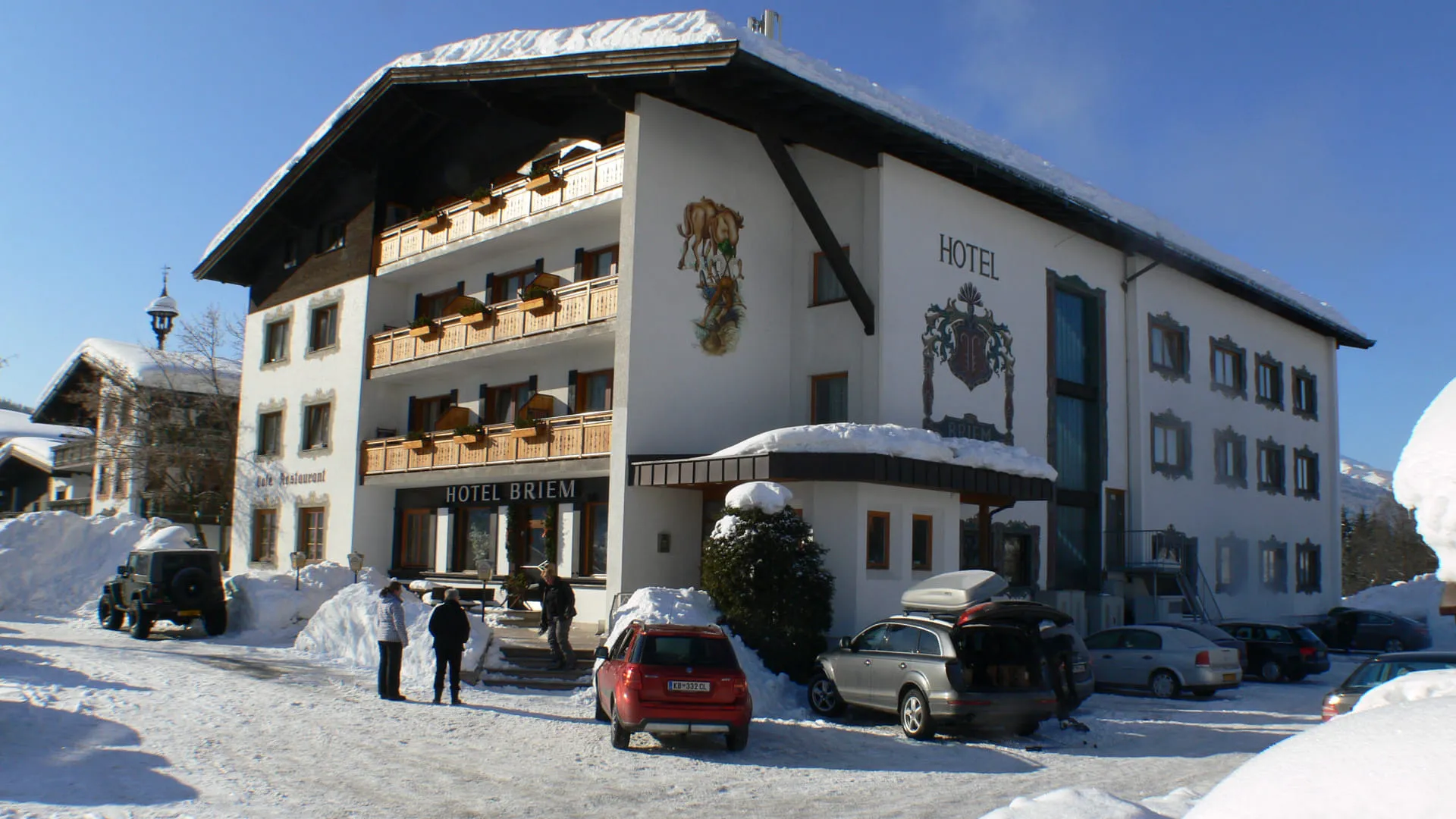 Schneebedecktes Hotel mit Menschen und Autos draußen
