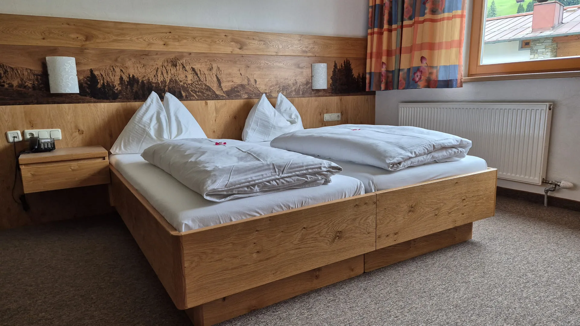 Helles Zimmer mit einem Doppelbett und Nachttischen