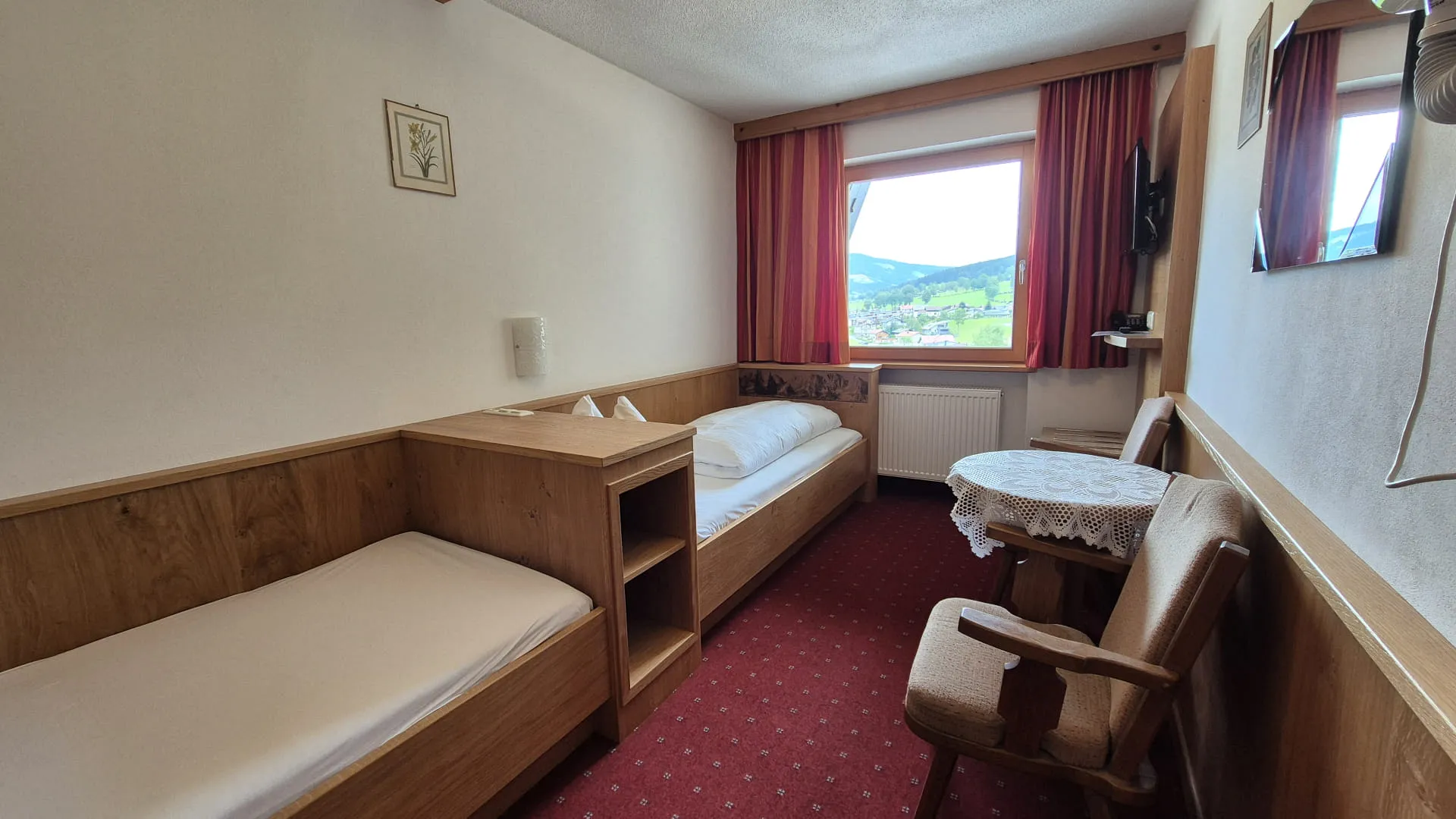 Zwei Einzelbetten in einem Zimmer mit Aussicht ins Grüne.